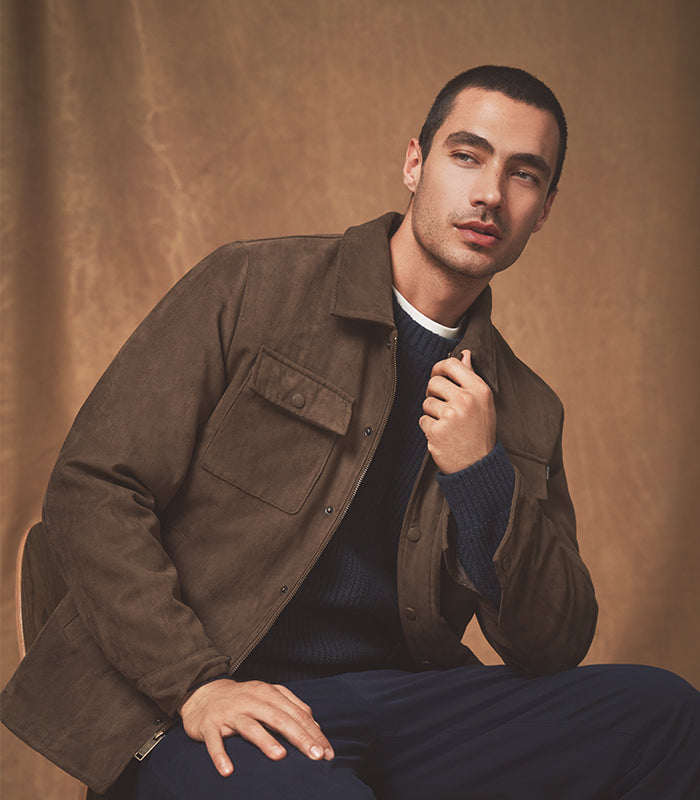 Man wearing a brown jacket sitting against a brown background
