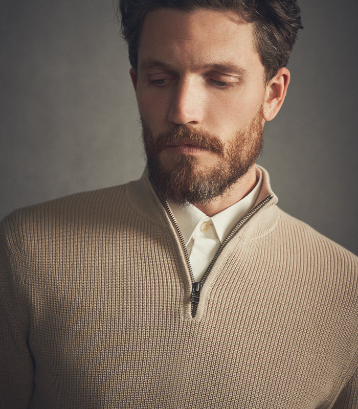 Man wearing a beige sweater with a neutral background