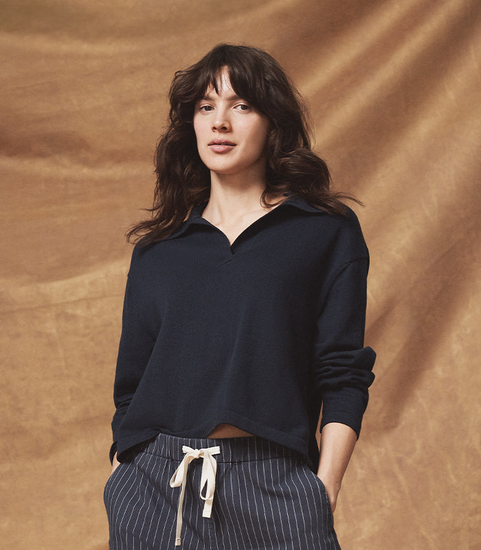 Woman wearing a dark blue shirt and striped pants against a brown background