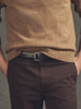 Person wearing a brown sweater and dark pants on a gray background