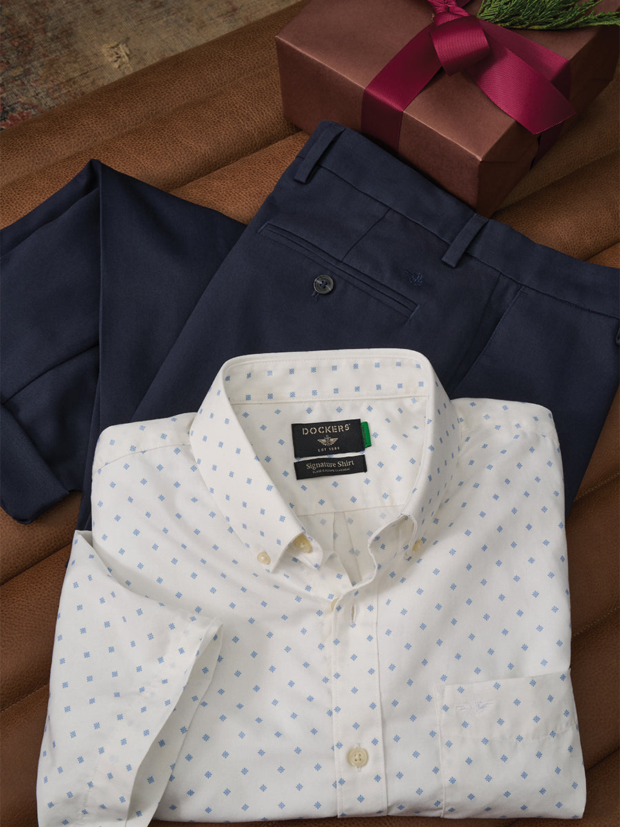 White dress shirt with blue polka dots and navy pants on a brown surface